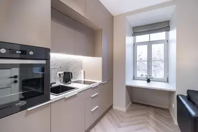 a kitchen with white cabinets and a black appliance at apartment with jacuzzi, old town in Vilnius