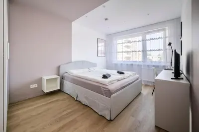 a white bedroom with a bed and a television at GoldenHugo Apartment in Vilnius
