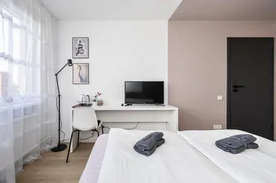 a white bedroom with a bed and a desk at GoldenHugo rooms in Vilnius