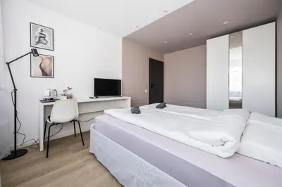 a white bedroom with a desk and a bed at GoldenHugo rooms in Vilnius