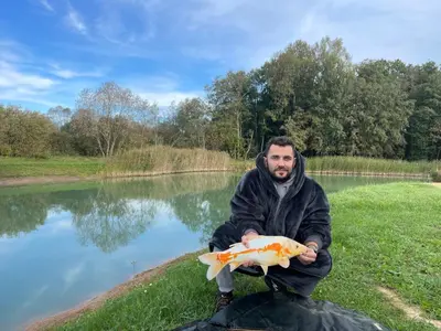 a man holding a fish in front of a lake at Pas Žuvelį in Stariai