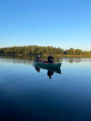two men are sitting in a boat on the water at Pas Žuvelį in Stariai