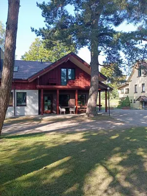 a red house with trees in front of it at Sodyba Prie Tvenkinio in Kurtuvėnai
