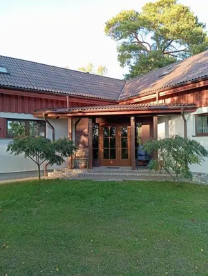 a home with a red and white house with a yard at Sodyba Prie Tvenkinio in Kurtuvėnai