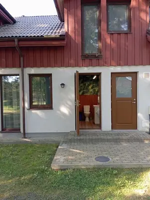 a red and white house with a door and a toilet at Sodyba Prie Tvenkinio in Kurtuvėnai