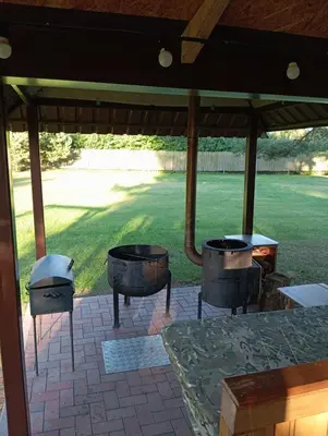 a porch with twoentedented tables and a grill at Sodyba Prie Tvenkinio in Kurtuvėnai