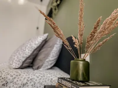 a green vase sitting on top of books next to a bed at Moody apartments in Šiauliai