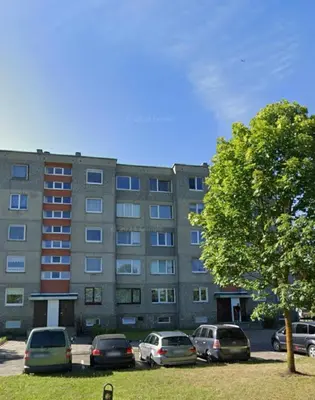 a large building with cars parked in a parking lot at Moody apartments in Šiauliai