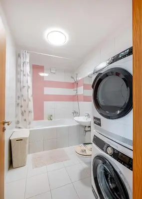 a bathroom with a washing machine and a tub at Onas apartament 2 with private parking in Kaunas