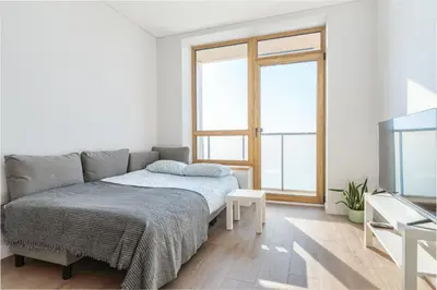a white bedroom with a bed and a tv at Two room Apartment - self check-in in Vilnius