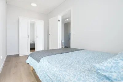 a white bedroom with a bed with a blue comforter at Two room Apartment - self check-in in Vilnius