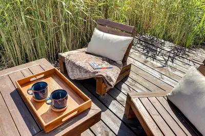 a wooden deck with a chair and a tray with cups at Meldai in Pabradė