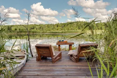 a wooden dock with a table and chairs on a lake at Meldai in Pabradė