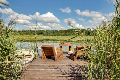 a wooden dock with a table and chairs on a lake at Meldai in Pabradė