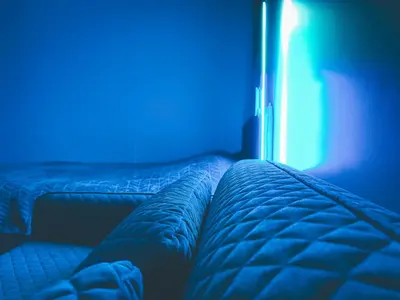 two beds in a room with a blue light at Cozy Ozo apartments, free parking! in Vilnius