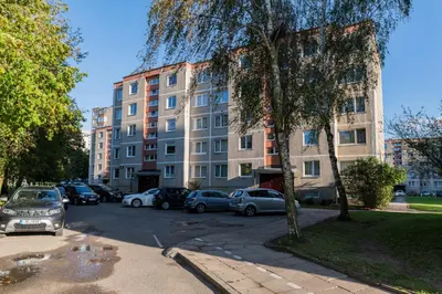 a parking lot with cars parked in front of a building at Malena Apartments in Šiauliai