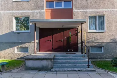 a building with a red door with stairs in front at Malena Apartments in Šiauliai
