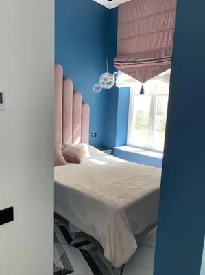 a bedroom with a bed with blue walls and a window at Apartment Gedimino 22 in Vilnius