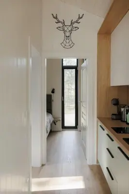 a white kitchen with a door to a bedroom at Vienis glamping - cozy and private forest house in Randamonys