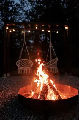 a fire pit in the yard at night with lights at Vienis glamping - cozy and private forest house in Randamonys
