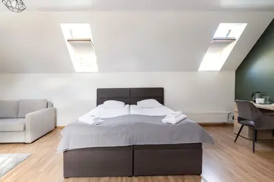 a bedroom with a bed and a couch and windows at Avanti apgyvendinimas-restoranas in Biržai