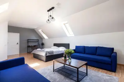 a living room with blue couches and a bed at Avanti apgyvendinimas-restoranas in Biržai