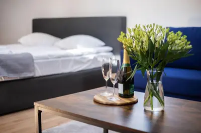 a table with two wine glasses and a vase with flowers at Avanti apgyvendinimas-restoranas in Biržai