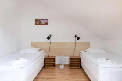 two beds in a room with white walls and wooden floors at Avanti apgyvendinimas-restoranas in Biržai