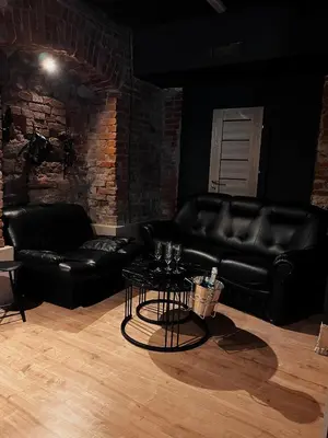 a living room with a black leather couch and a table at FETISH Room in Kaunas