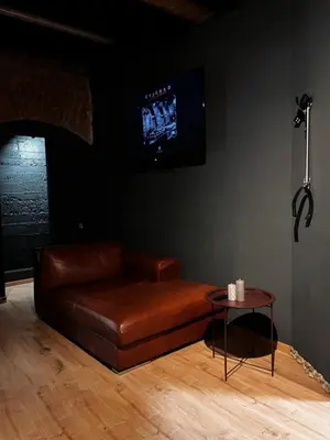 a brown leather couch in a living room with a table at FETISH Room in Kaunas