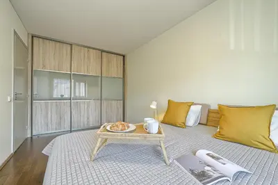 a room with a table and a bed with yellow pillows at Family Oasis Apartments x Free parking x SELF CHECK IN 24x7 in Vilnius