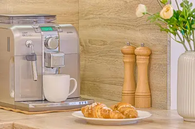 a coffee machine with a cup and a plate of croissants at Family Oasis Apartments x Free parking x SELF CHECK IN 24x7 in Vilnius