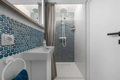 a bathroom with a shower with blue tiles at Vega - Whirlpool - Self Checkin in Vilnius