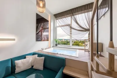 a living room with a blue couch and a tub at Vega - Whirlpool - Self Checkin in Vilnius
