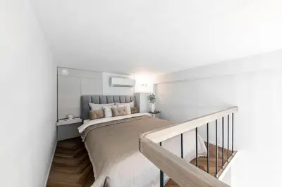 a bedroom with a large bed and a staircase at Vega - Whirlpool - Self Checkin in Vilnius