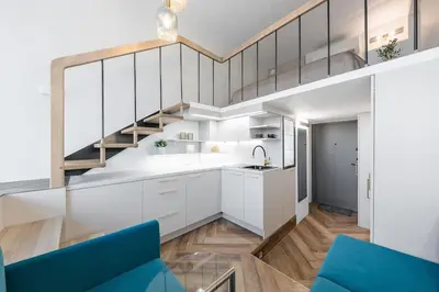 a kitchen with white cabinets and a spiral staircase at Vega - Whirlpool - Self Checkin in Vilnius