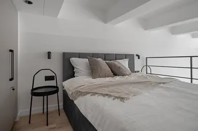 a bedroom with a large bed and a chair at Modern loft in City centre Self check-in No 45 in Vilnius