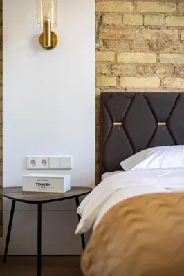 a bedroom with a bed and a table with a clock on it at cohost I Brand New Apt, w-AC in a Central Location in Vilnius