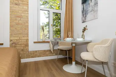 a bedroom with a bed and a table and two chairs at cohost I Brand New Apt, w-AC in a Central Location in Vilnius