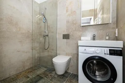 a bathroom with a toilet and a washing machine at cohost I Brand New Apt, w-AC in a Central Location in Vilnius