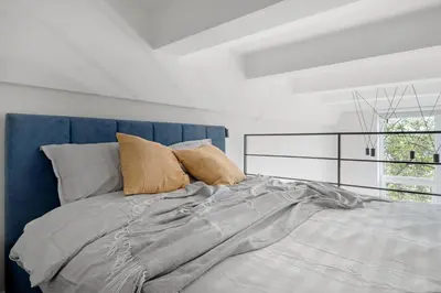 a bedroom with a bed with a blue headboard and pillows at Modern loft in City centre Self check-in No 47 in Vilnius