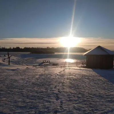 a sun is setting over a snow covered field at Sodyba Po klevais in Meištai