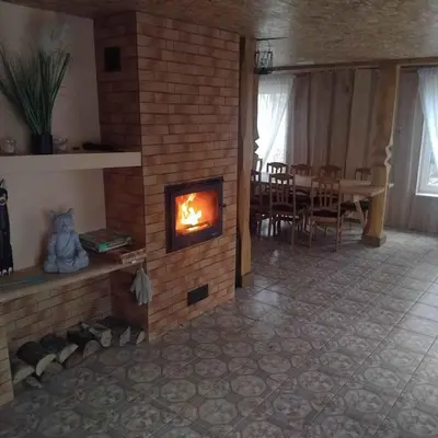 a living room with a fireplace and a dining table at Sodyba Po klevais in Meištai