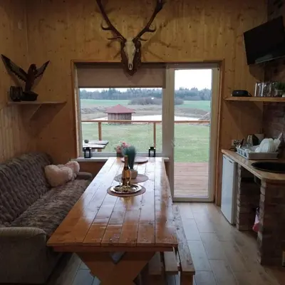 a living room with a wooden table and a large window at Sodyba Po klevais in Meištai