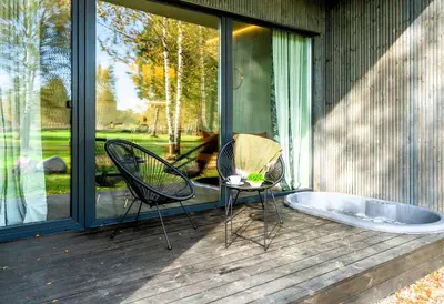 a patio with two chairs and a tub on a deck at Beržynė Villas in Liepiškės