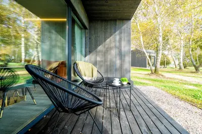 two chairs and a table on a porch at Beržynė Villas in Liepiškės