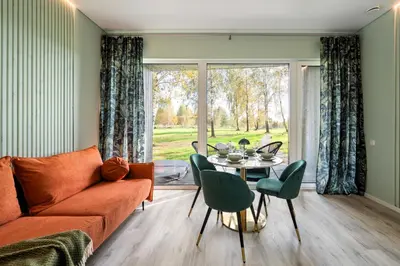 a living room with a couch and a table and chairs at Beržynė Villas in Liepiškės