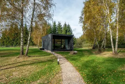 a black house in a field with a path at Beržynė Villas in Liepiškės