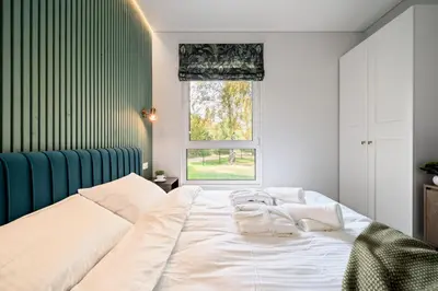 a bedroom with a large white bed and a window at Beržynė Villas in Liepiškės