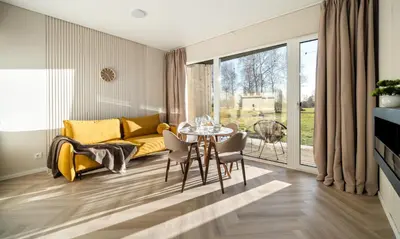 a living room with a table and a yellow couch at Beržynė Villas in Liepiškės